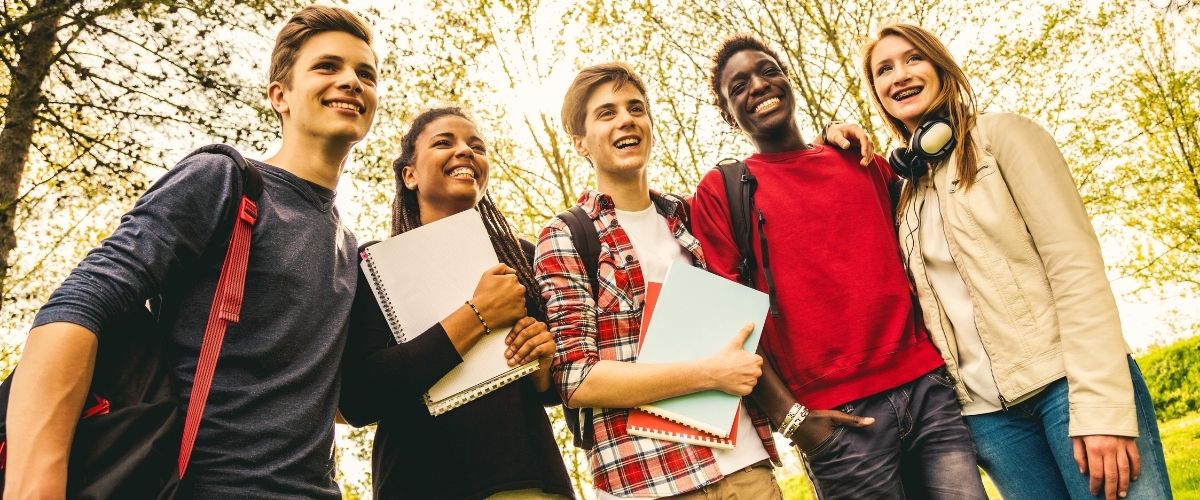 Groupe d’adolescents souriants discutant en plein air, illustrant l’importance du respect, du consentement et de l’empathie à travers les jeux éducatifs.