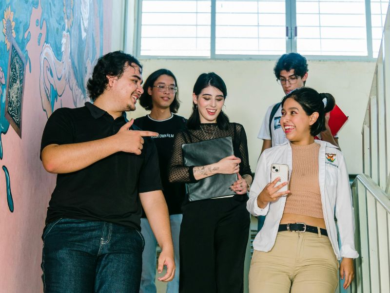 Groupe d’adolescents échangeant et discutant ensemble dans un espace scolaire, illustrant le dialogue, l’écoute et la communication sans conflit.