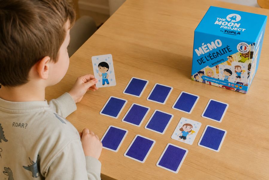 enfant jouant au jeu Mémo de l’égalité Topla avec cartes retournées sur une table pour développer la concentration et l’expression des émotions
