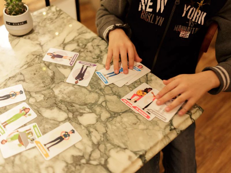 Enfant jouant à un jeu de cartes éducatif sur les métiers, pour développer la concentration et la mémoire — jeu Topla