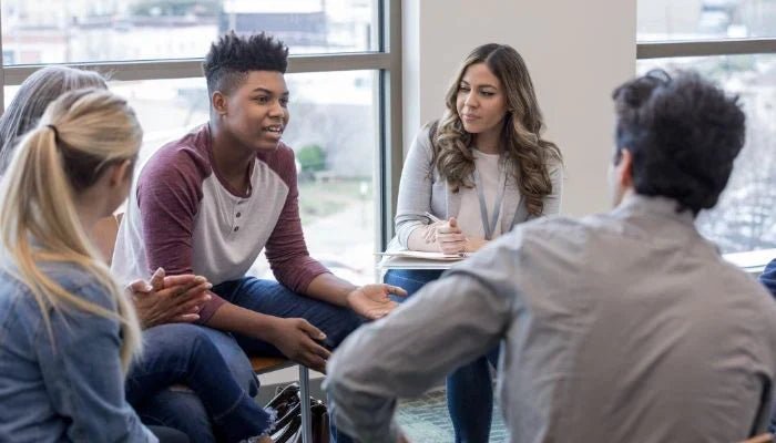 Groupe d’adolescents échangeant avec un enseignant lors d’un atelier d’éducation à la vie affective, relationnelle et sexuelle au lycée.