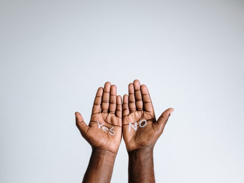 Mains ouvertes montrant les mots “Yes” et “No” inscrits dans les paumes – symbole du consentement dans le jeu inclusif