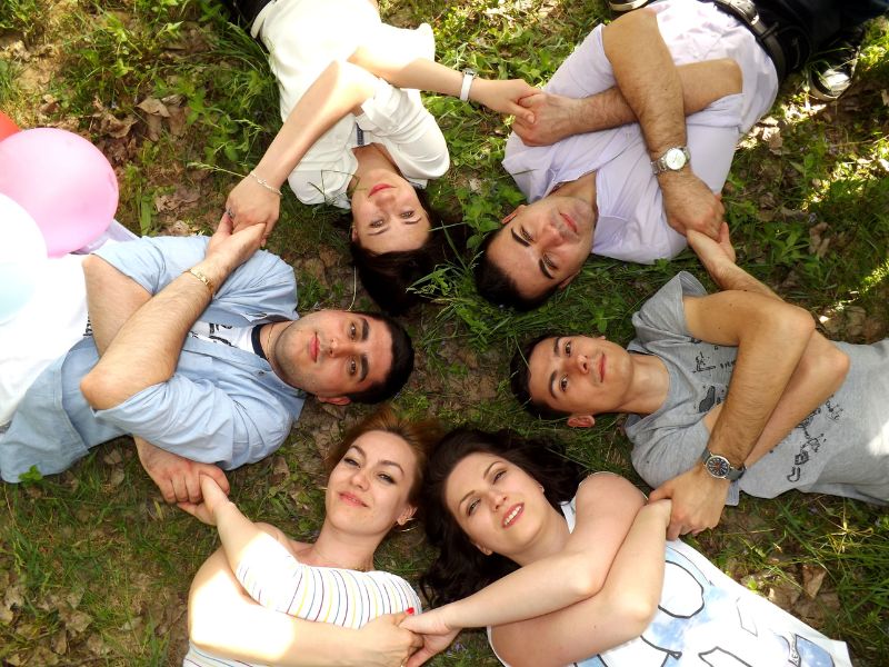 Groupe d’amis allongés en cercle, main dans la main, lors d’une soirée conviviale en plein air.
