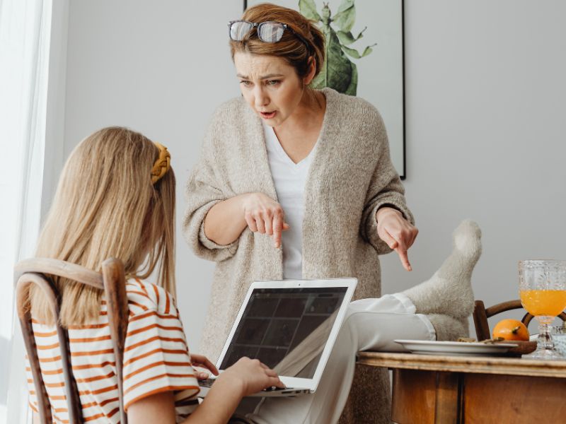 Parent échangeant avec un enfant à propos de l’utilisation d’un écran à la maison, illustrant le dialogue familial autour des usages numériques.