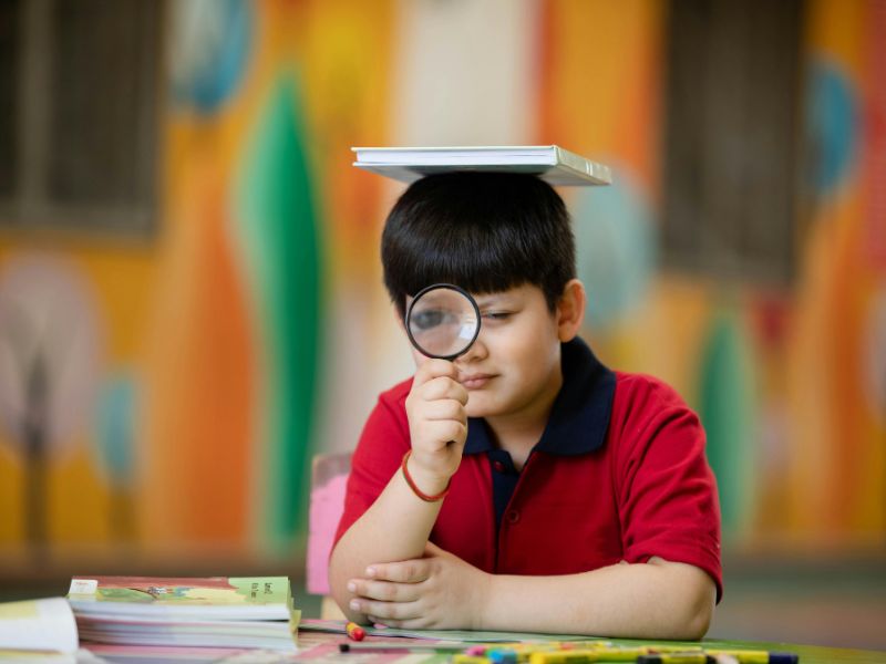 Enfant concentré observant un objet avec une loupe, illustrant l’attention, la curiosité et la focalisation lors d’une activité ludique